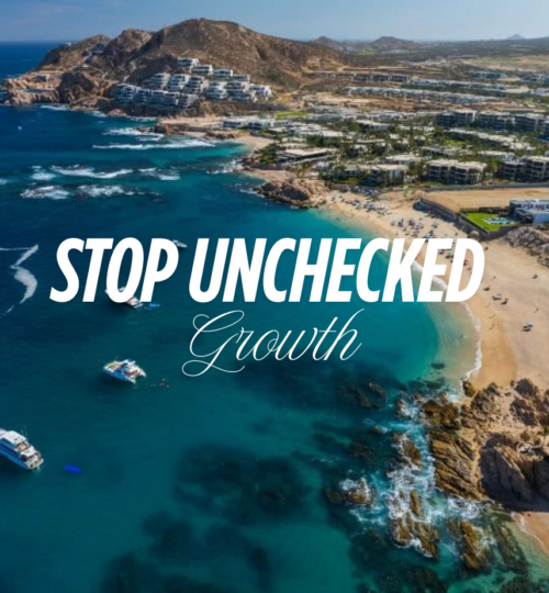 Low-rise terracotta luxury resorts along the Los Cabos coastline with desert mountains and Sea of Cortez representing the natural landscape that Los Cabos sustainable development must protect from unchecked vertical growth